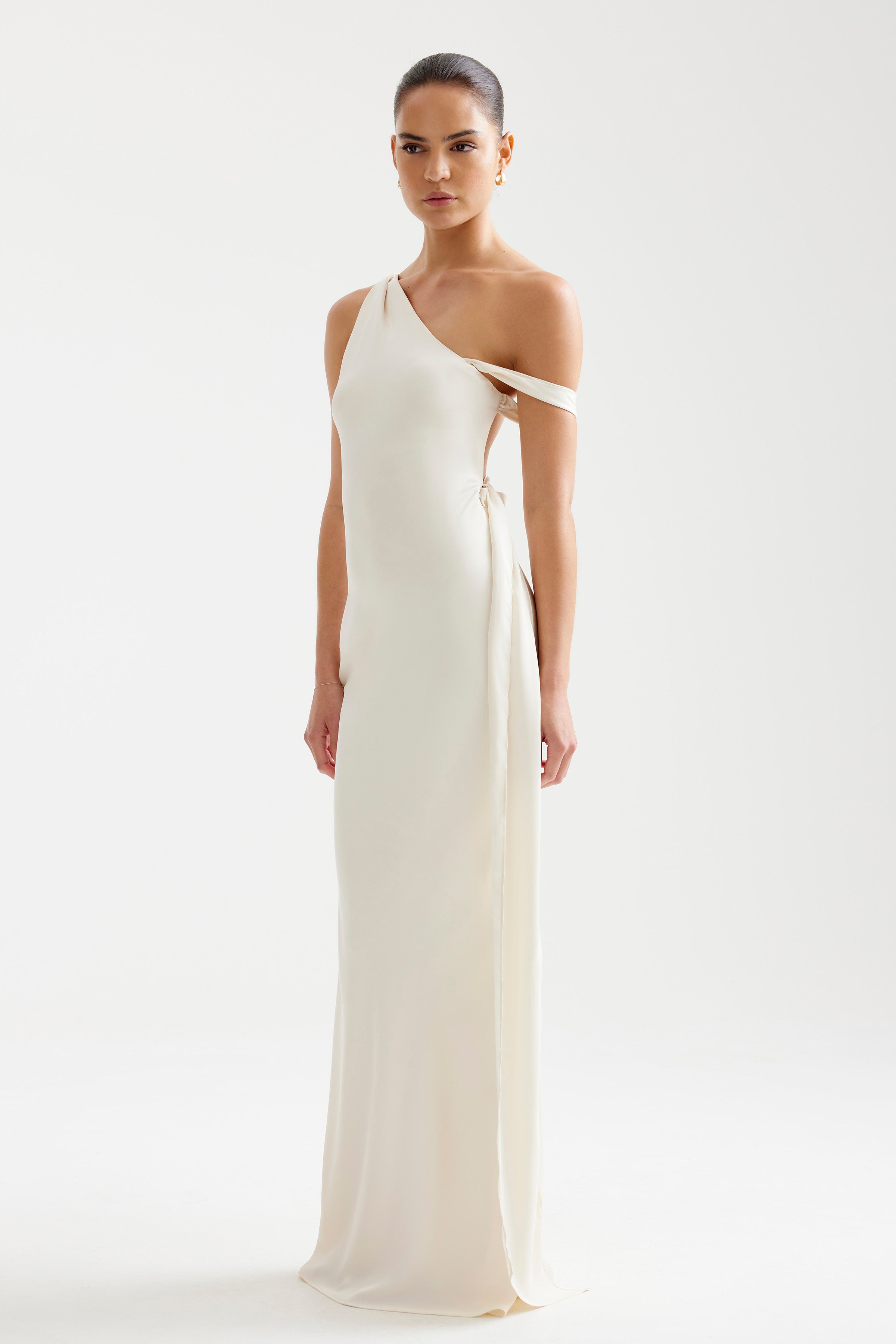 Ara Dress featuring a sleek backless design with asymmetrical straps and a small train in soft oyster for formal occasions