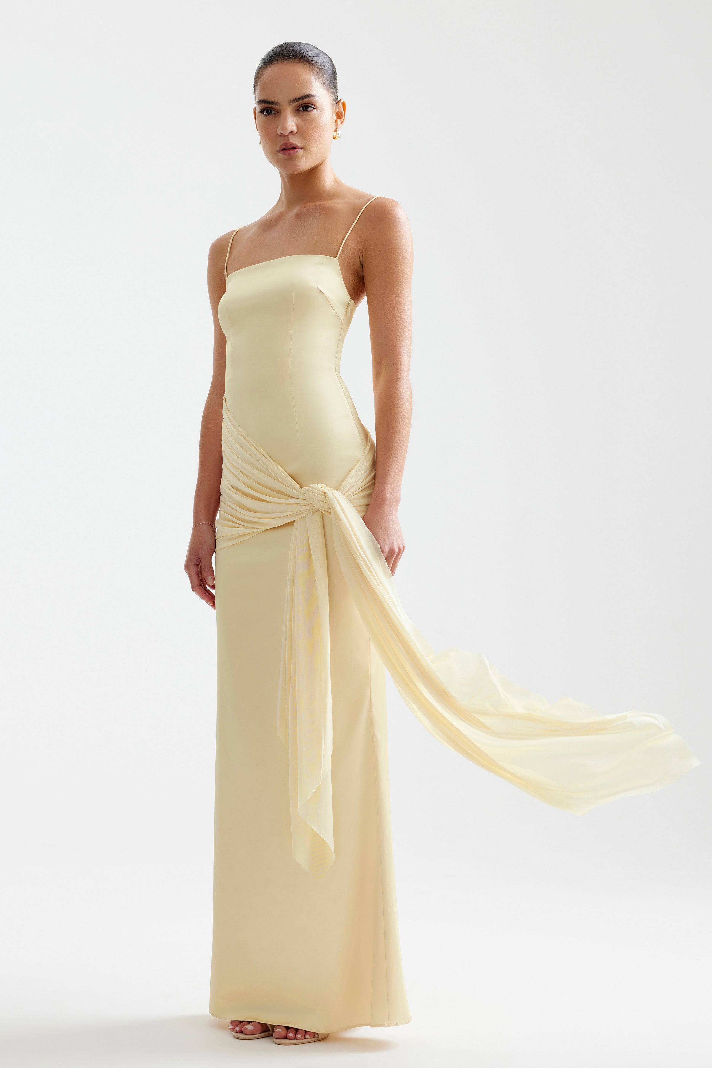 Ayla Dress featuring a sleek fitted silhouette with delicate straps and a flowing sash in limoncello for formal wear