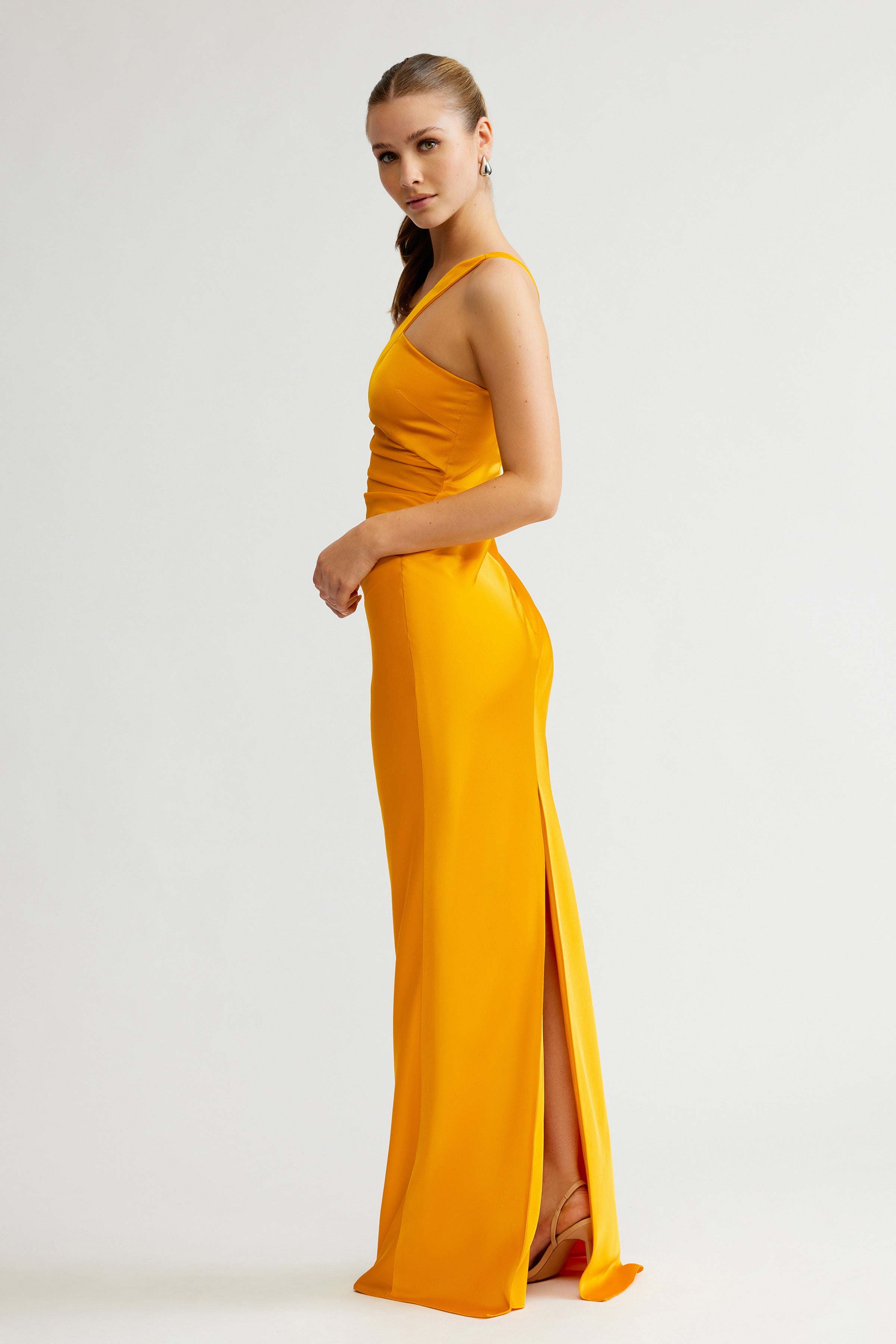 Clarisse Dress featuring a sleek silhouette with a side split and single strap in saffron satin for formal occasions