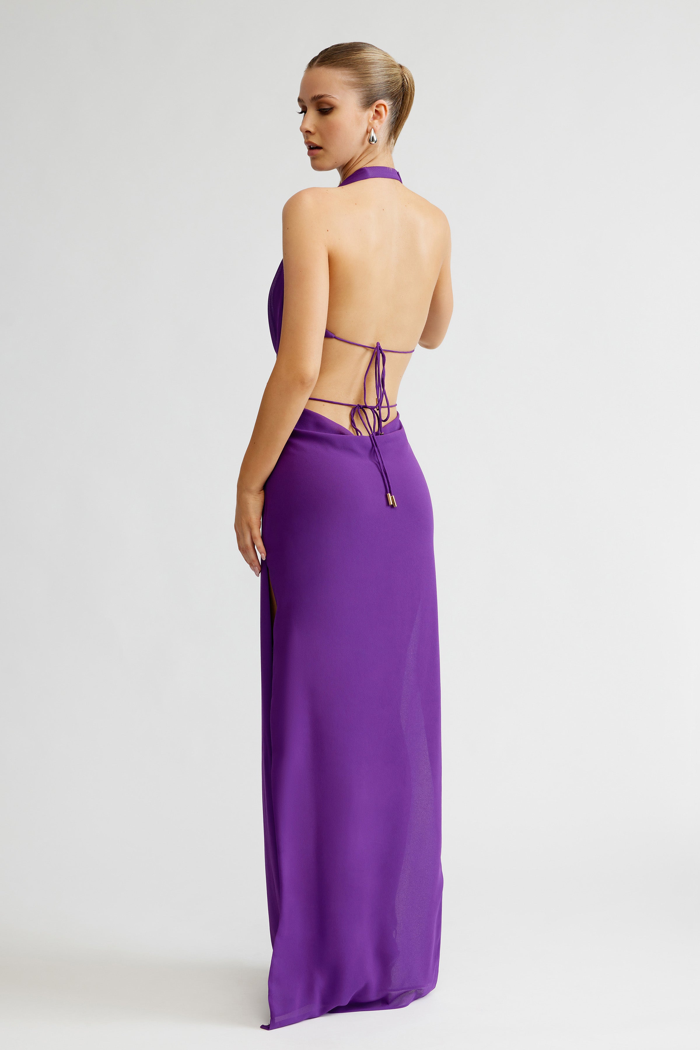 Clio Set featuring an open-back halter top with tie details and a long violet skirt with side slit for formal occasions