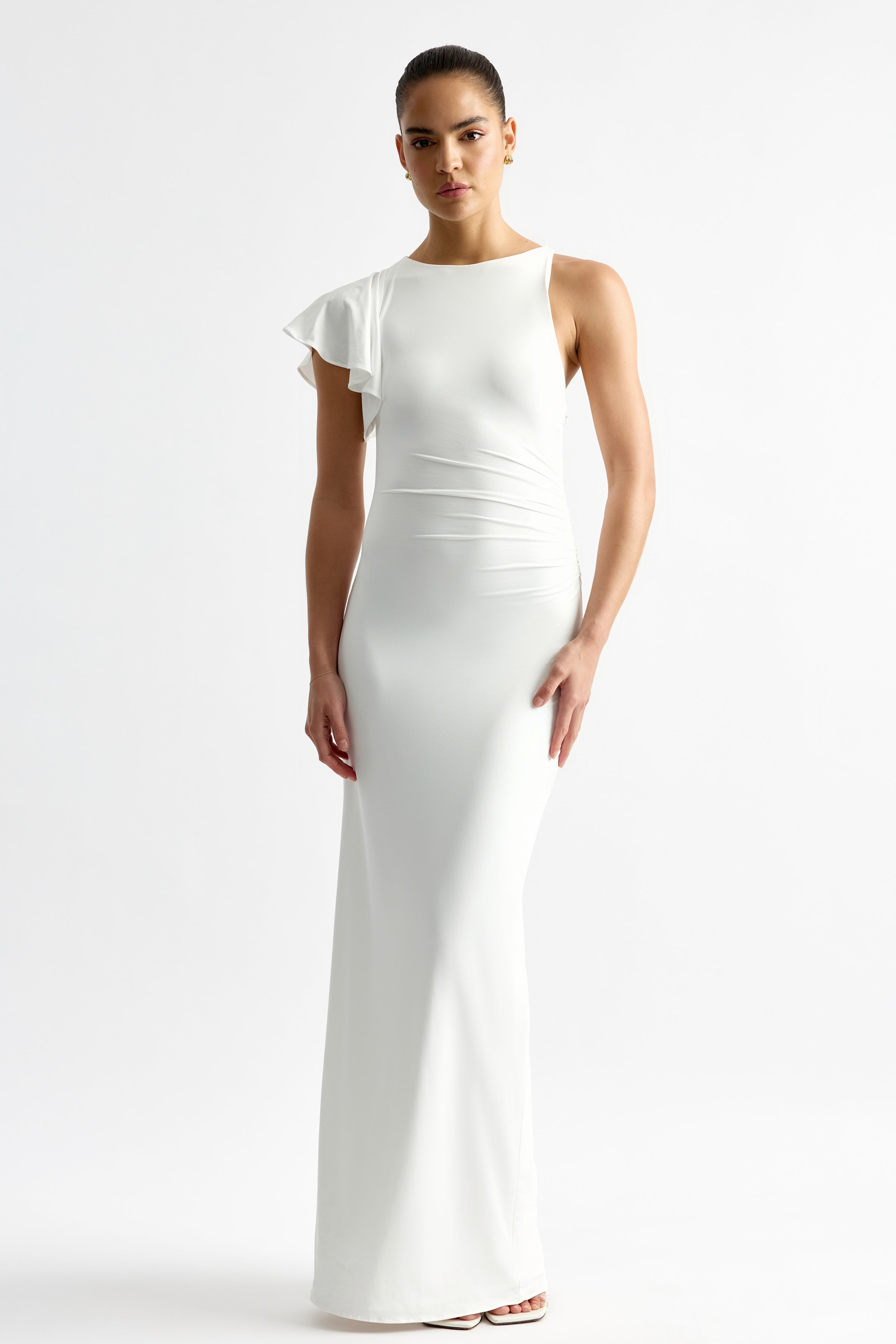 Diane Dress featuring a sleek fitted maxi silhouette with one ruffled sleeve in ivory by Studio Lexi for formal occasions