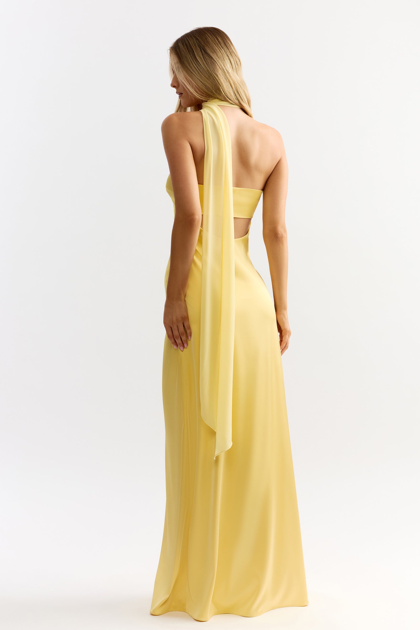 Hali Dress featuring a strapless backless silhouette with flowing halter detail in sunflower yellow by Studio Lexi