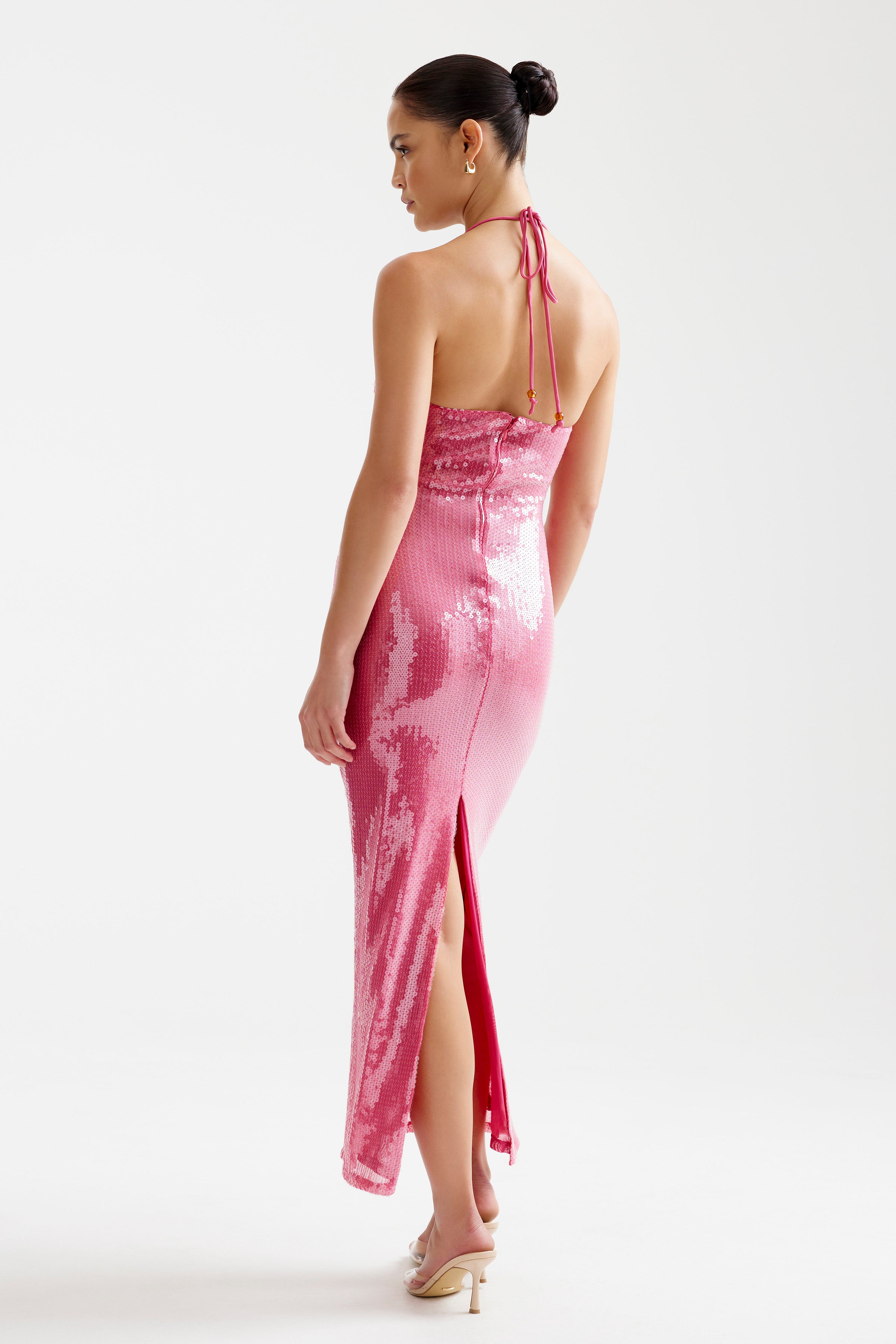 Imma Dress features a backless halter design with a side slit in shimmering bright melon for cocktail and party wear