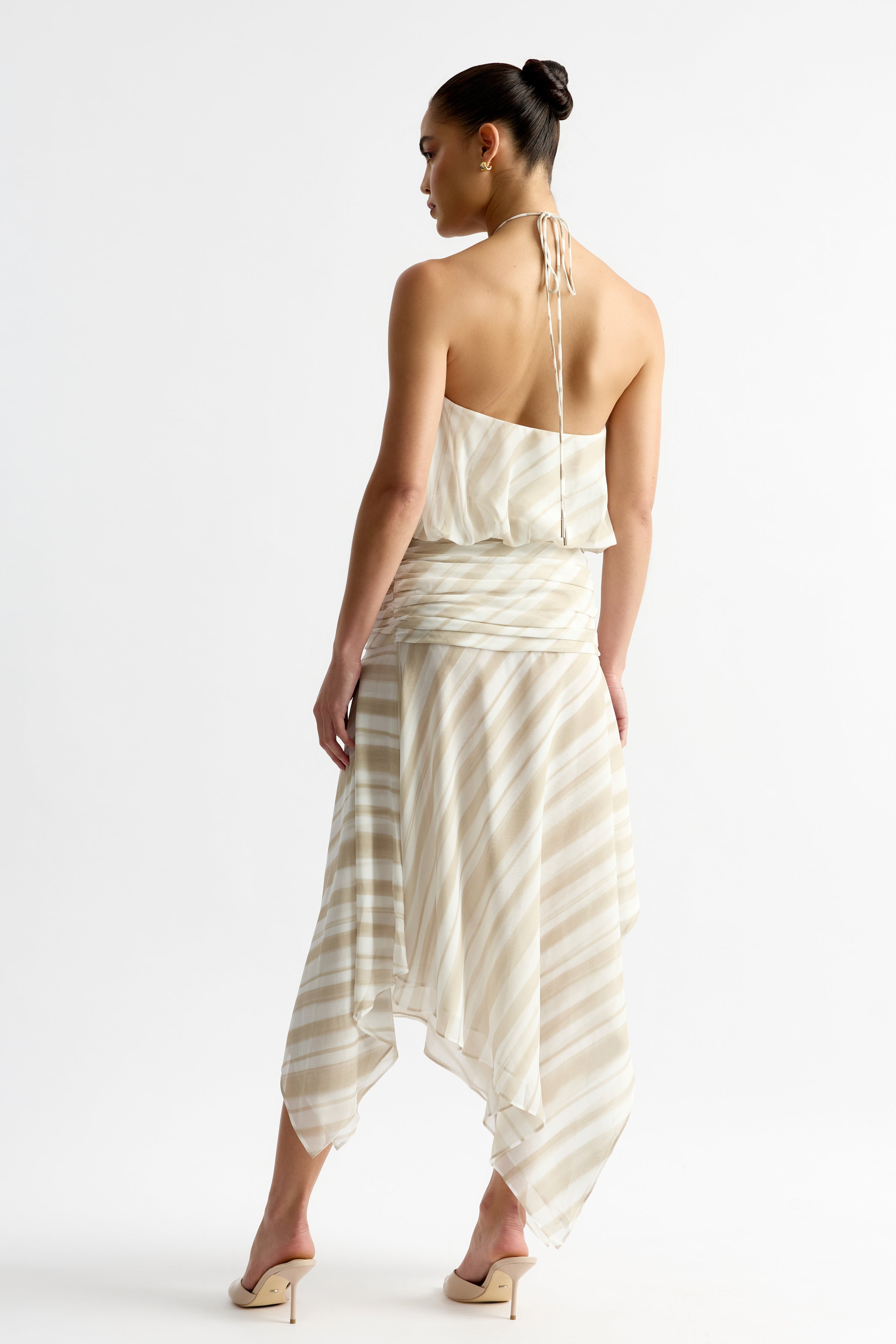 Jean Dress featuring a backless halter top and flowing handkerchief hem in beige stripe print by Studio Lexi
