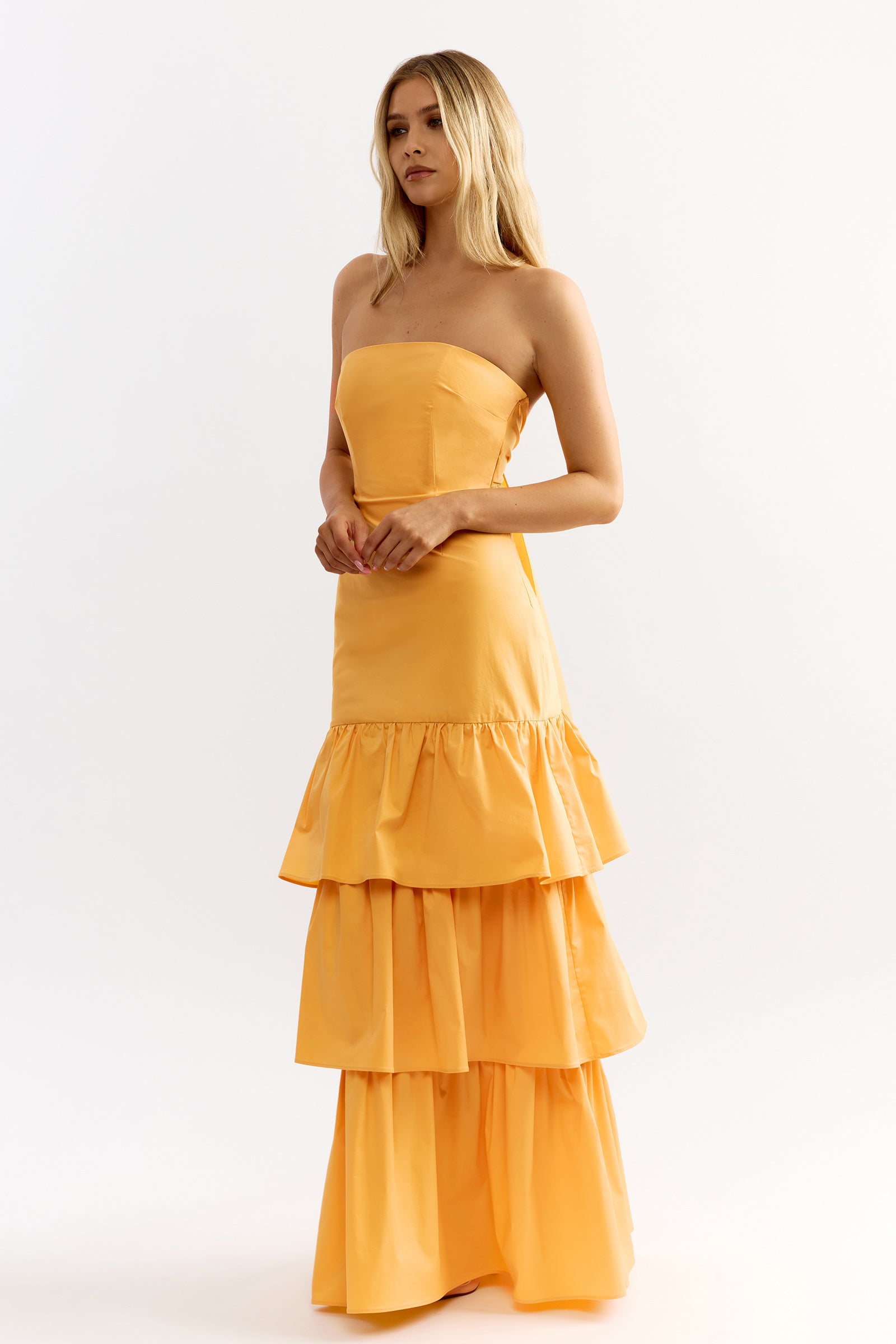 Katy Dress featuring strapless silhouette and tiered skirt in honey yellow with elegant backless detail by Studio Lexi