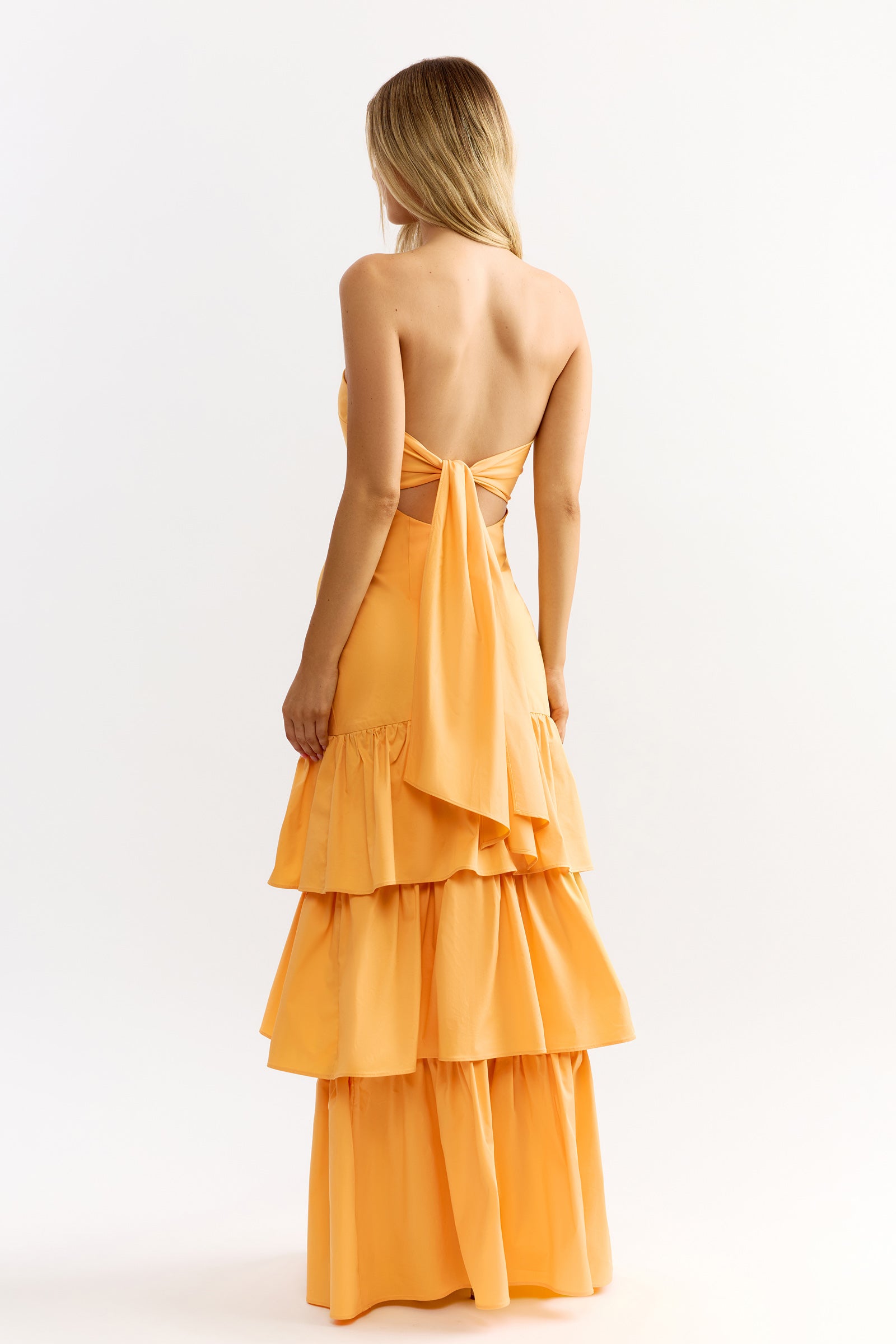 Katy Dress featuring tiered skirt and elegant backless design with bow detail in warm honey by Studio Lexi