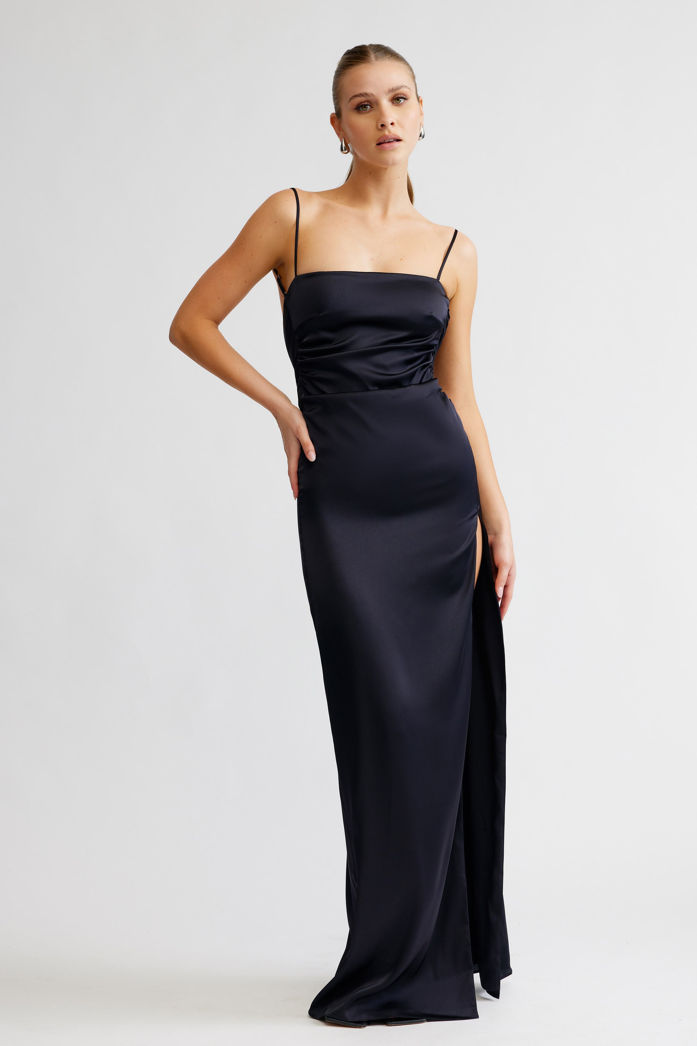 Kiri Dress featuring a sleek black satin fabric with thin straps and a high side split for formal occasions