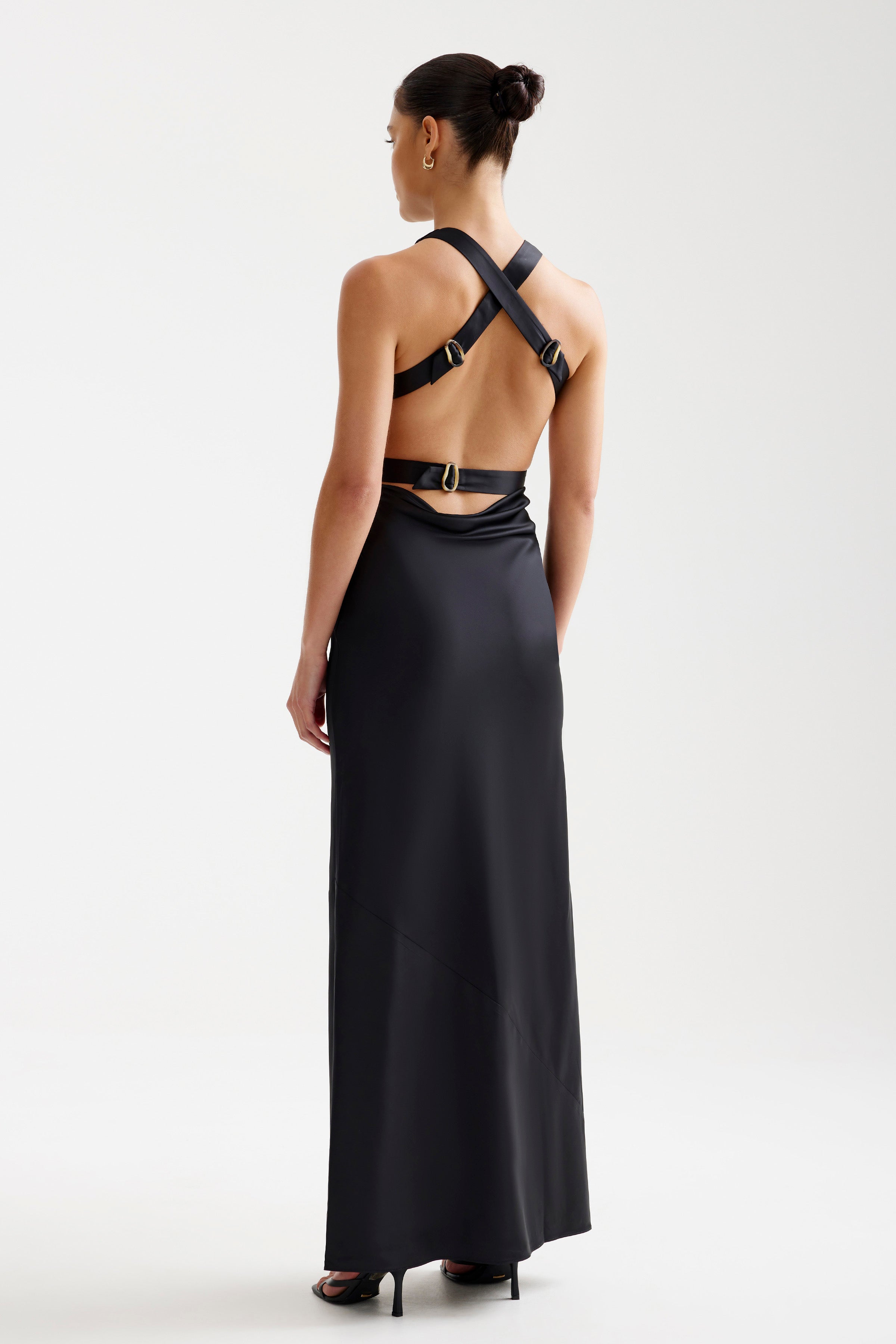 Liora Dress featuring a backless cross-strap design with buckle details in sleek black for formal occasions