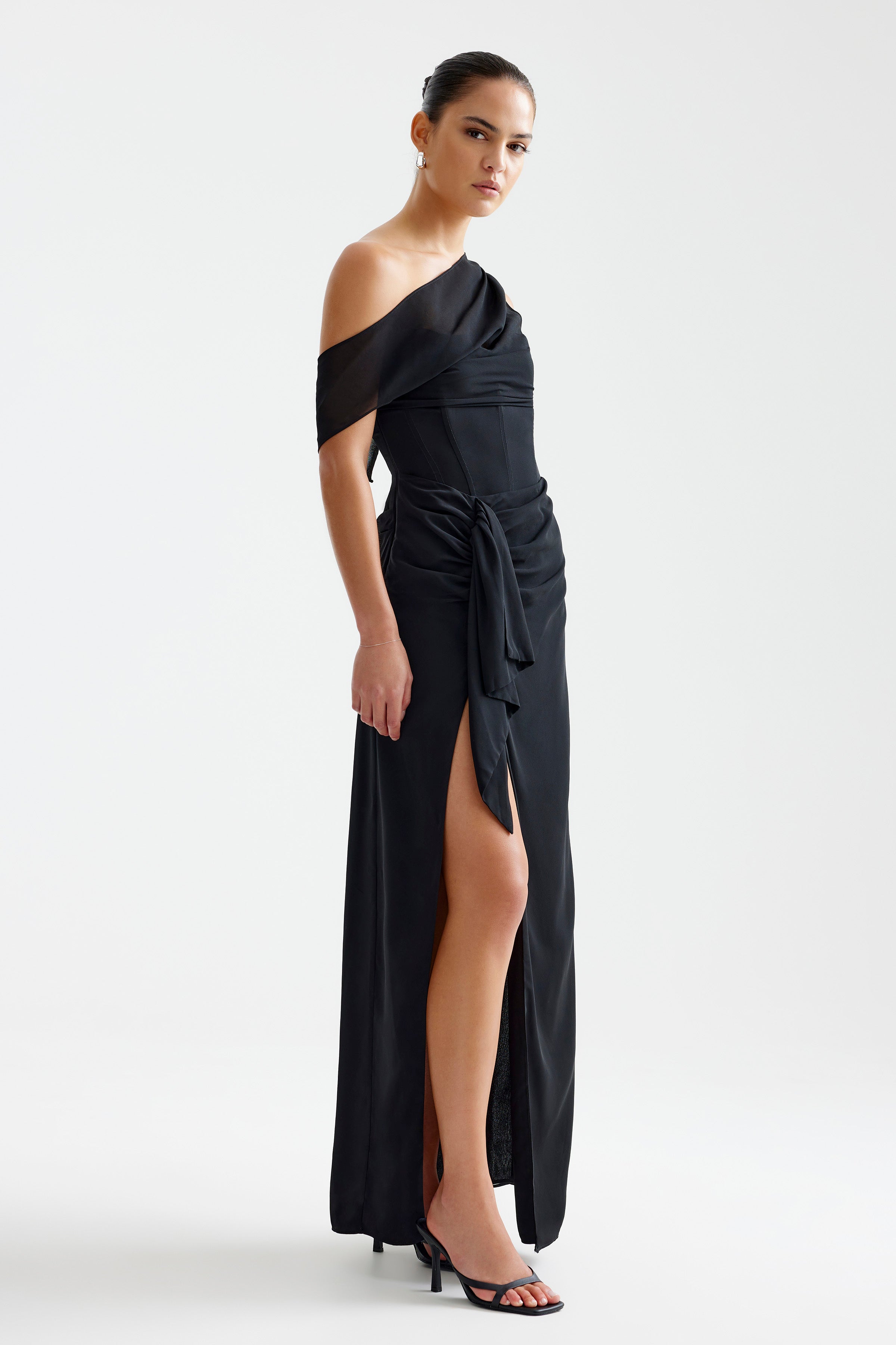Mirelle Dress featuring an off-shoulder sleeve with a draped tie waist and high side split in black by Studio Lexi