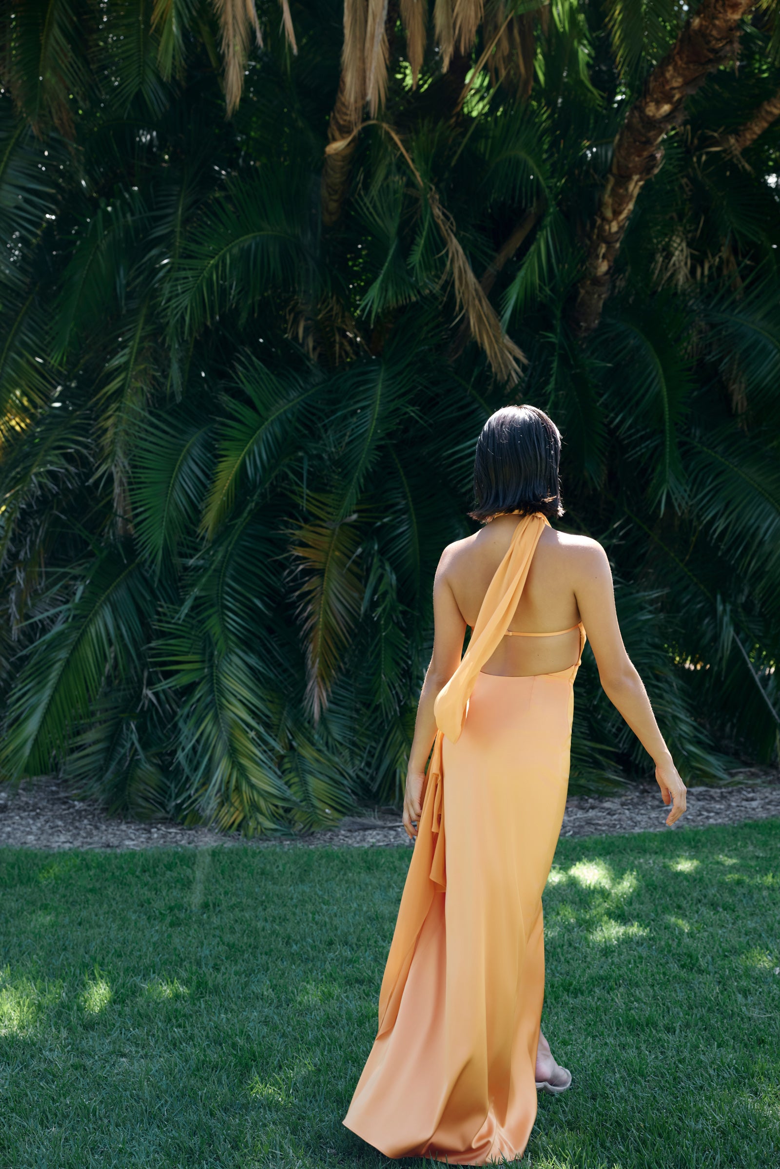 Mona Dress featuring a backless halter neck and flowing skirt in orange for formal and wedding guest occasions by Studio Lexi