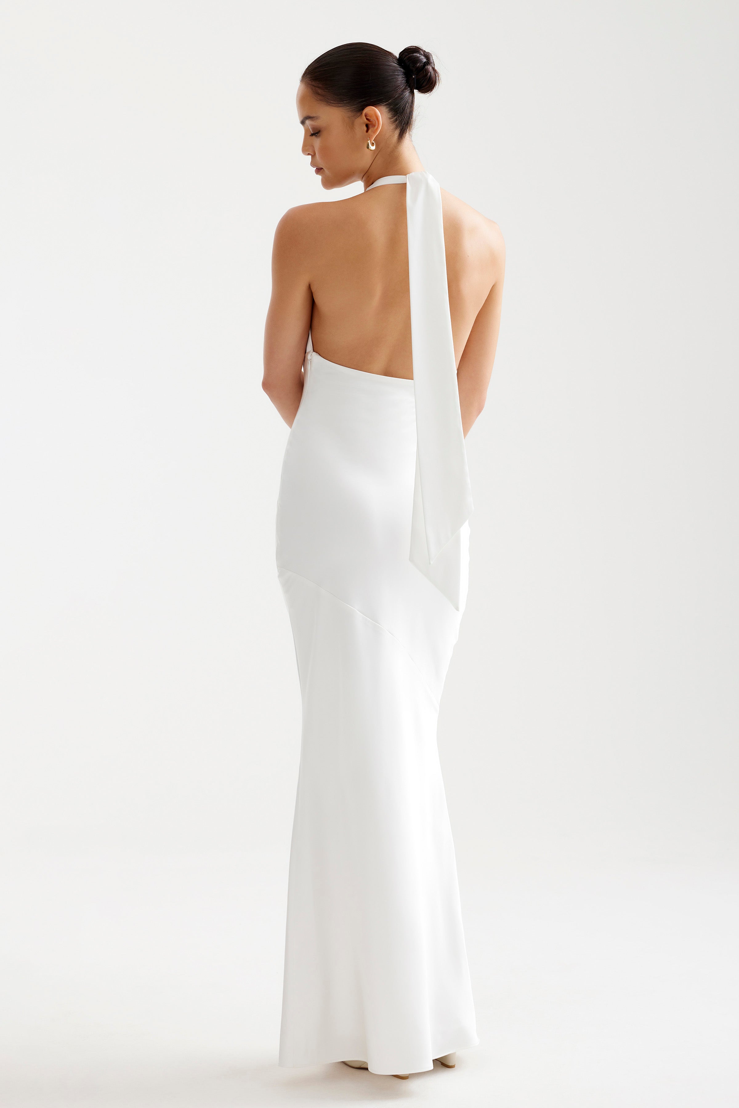 Novia Dress featuring a backless halter design with draped tie detail in elegant white for formal and black tie events by Studio Lexi