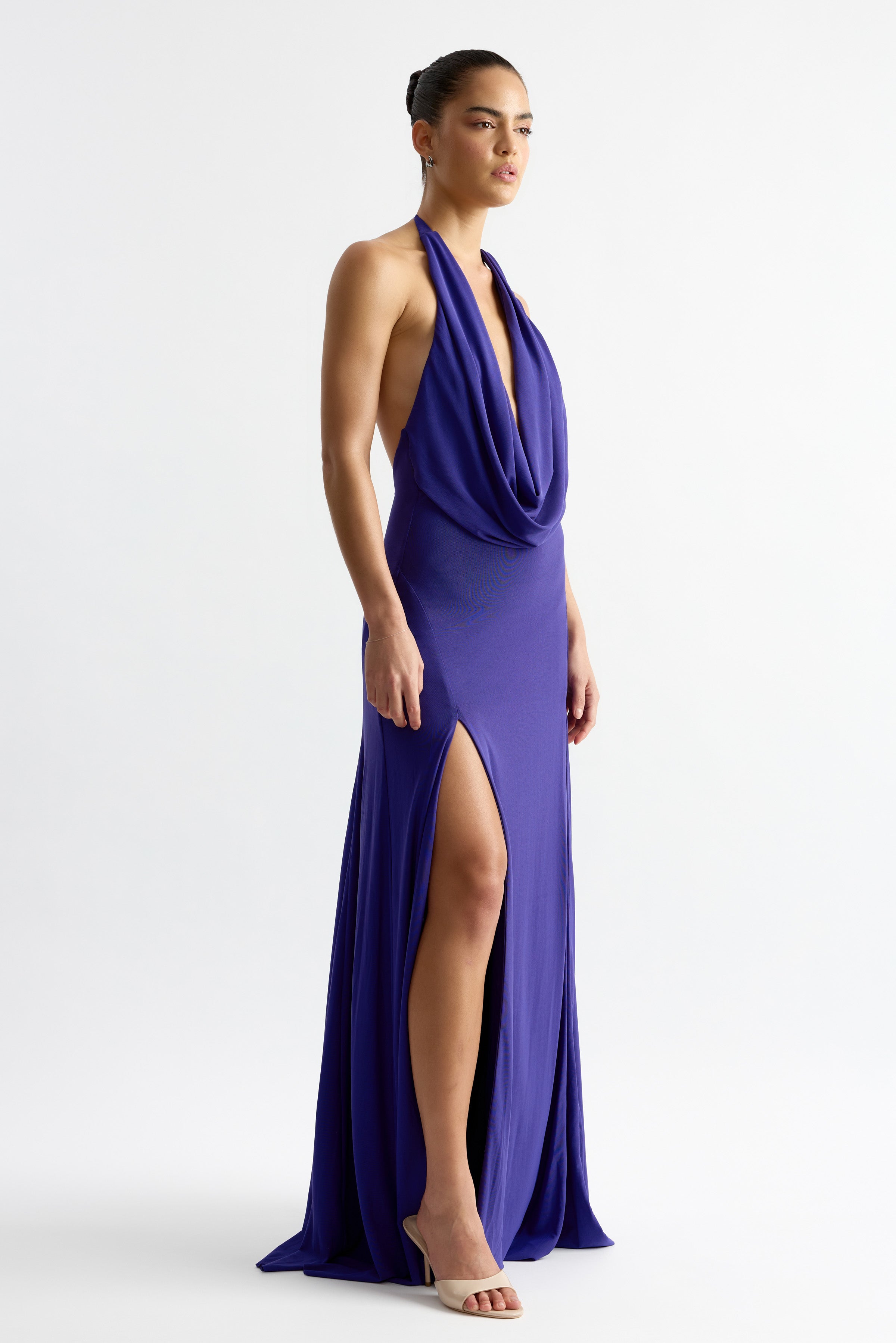Model wearing Savannah Dress - Indigo with low draped cowl neckline and twin splits, gallery position 4 portrait view.
