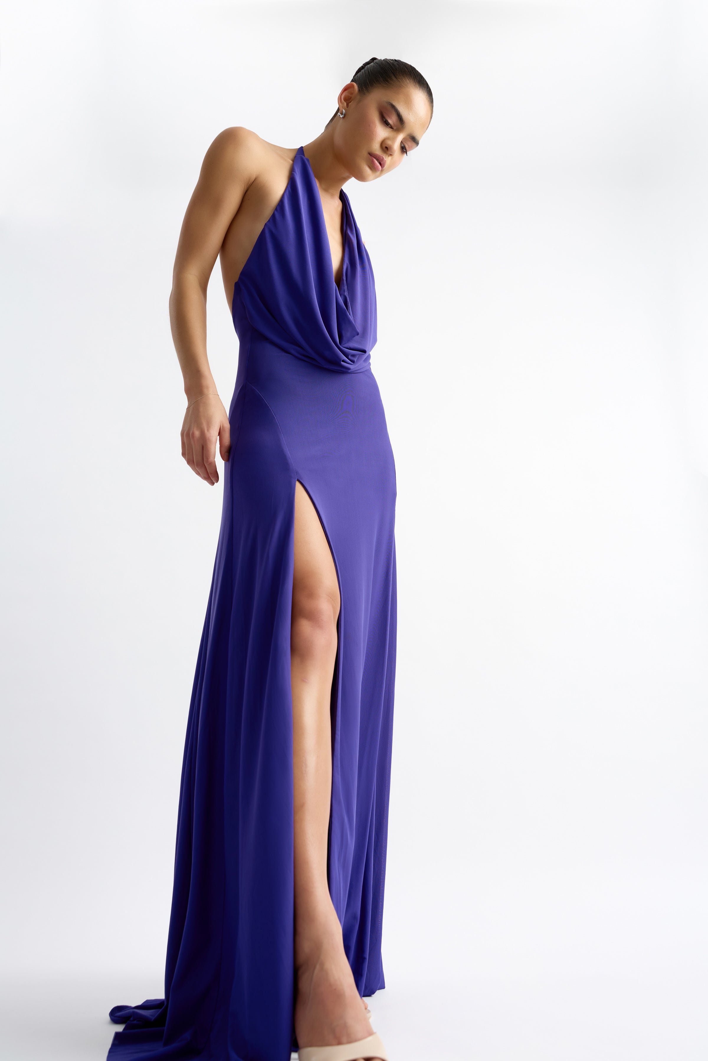 Woman wearing Savannah Dress - Indigo with draped halter and thigh-high split, portrait orientation, gallery position 1