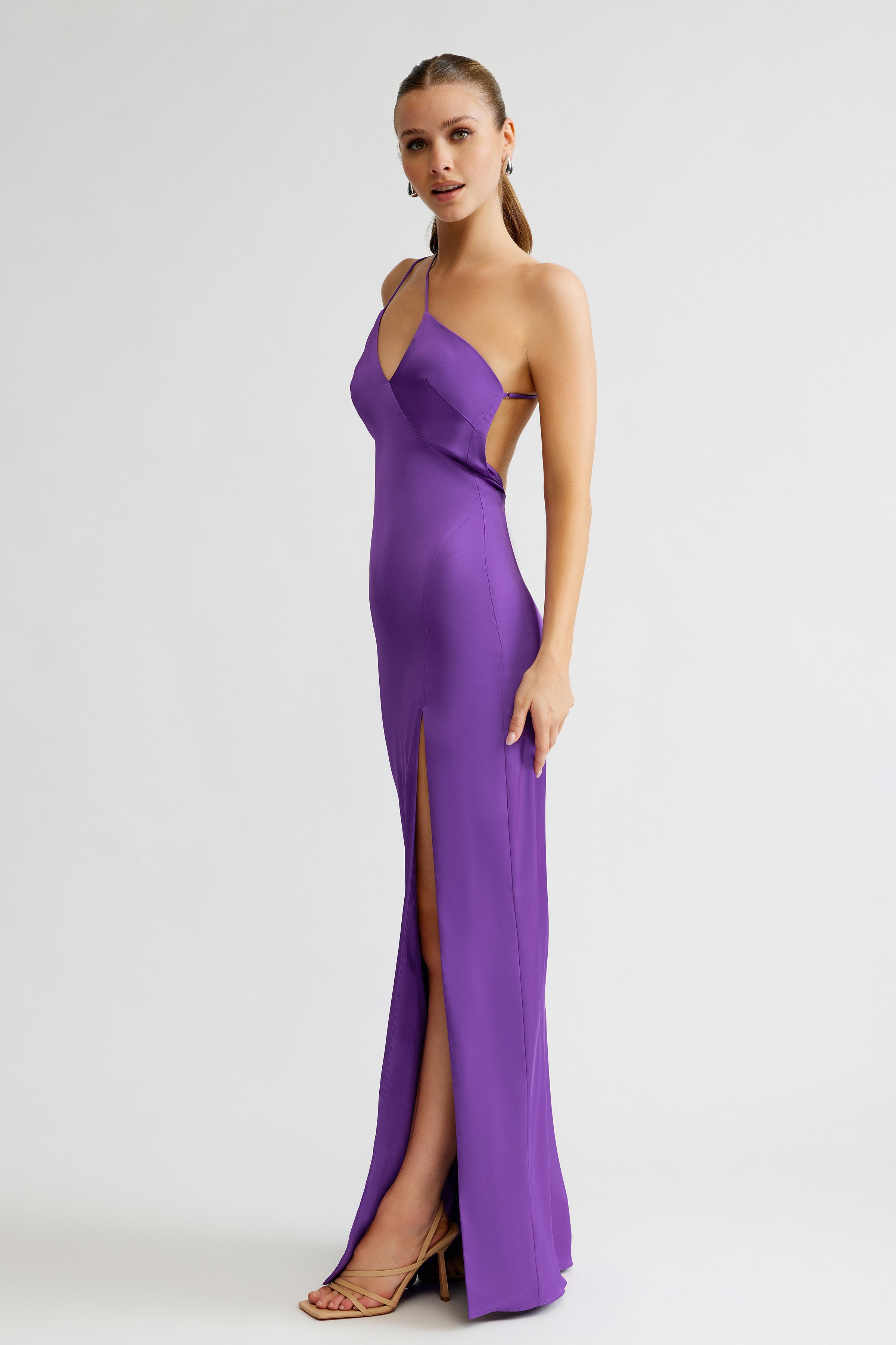 Thalia Dress featuring a sleek silhouette with a thigh-high split and backless design in vibrant violet satin
