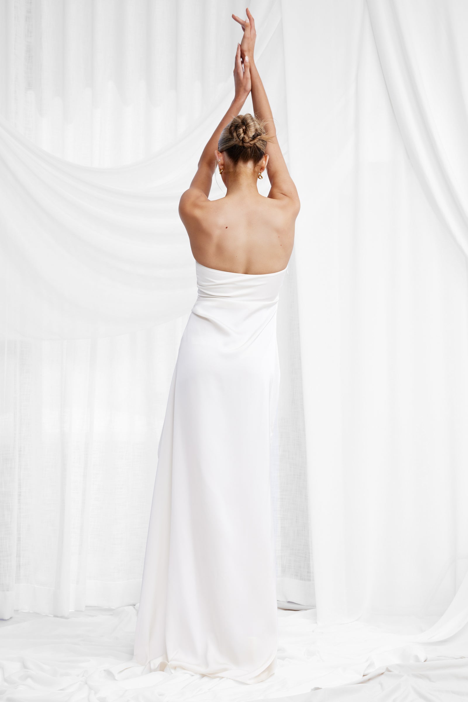 Alzira Dress - Oyster shown from back in portrait orientation, highlighting the strapless design and smooth satin fabric