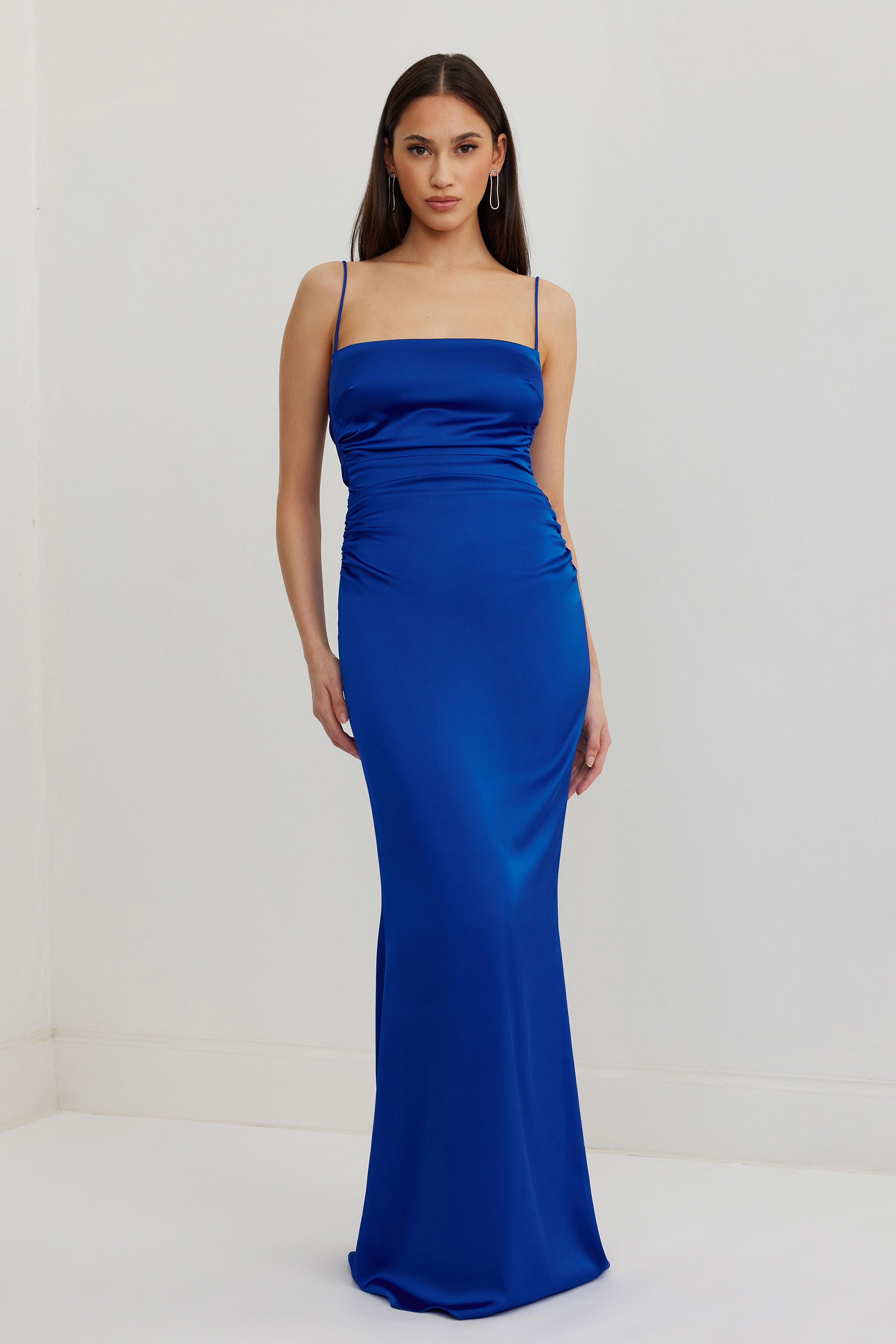 Ivy Dress featuring a sleek fitted silhouette with ruched sides and thin straps in vibrant cobalt satin for formal events
