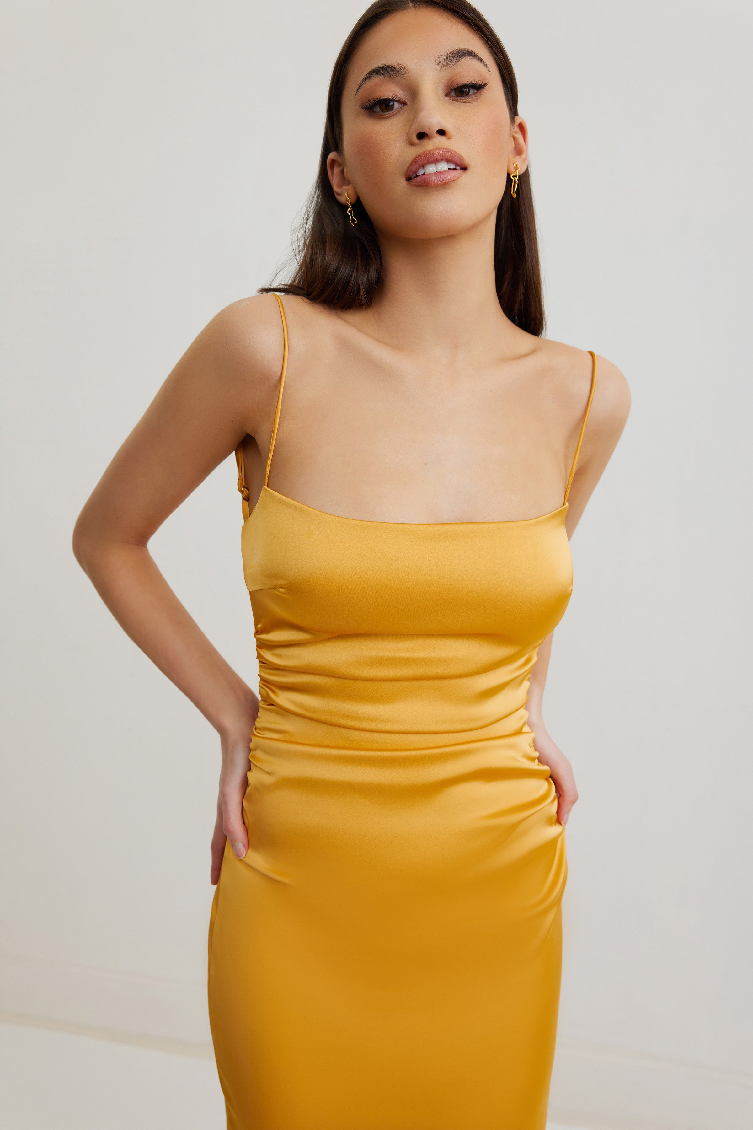 Ivy Dress featuring a sleek satin finish with slim straps and ruched side details in honey for formal occasions