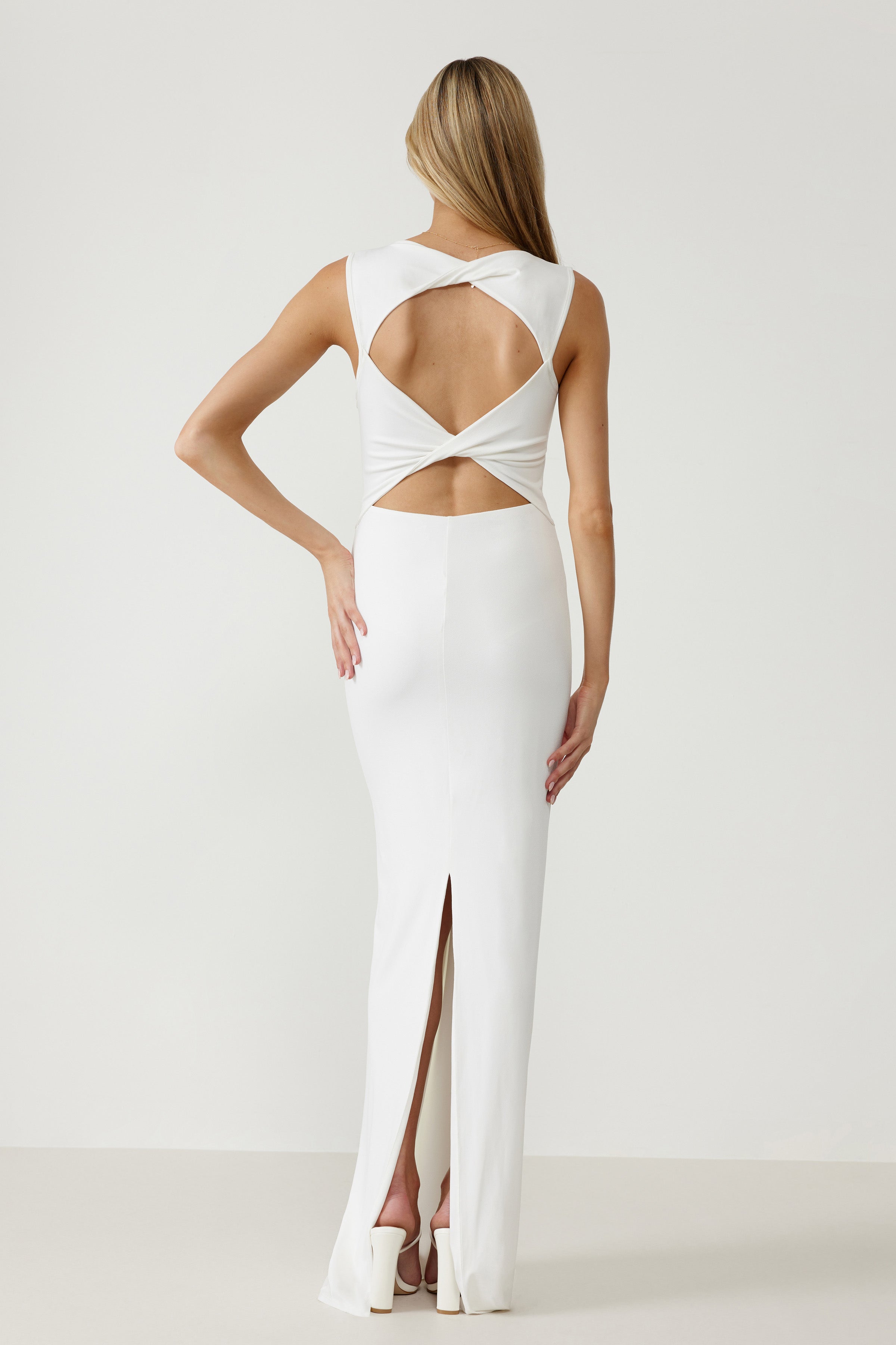 Lara Dress featuring a backless design with cutout details and a rear split in white stretch fabric for formal occasions