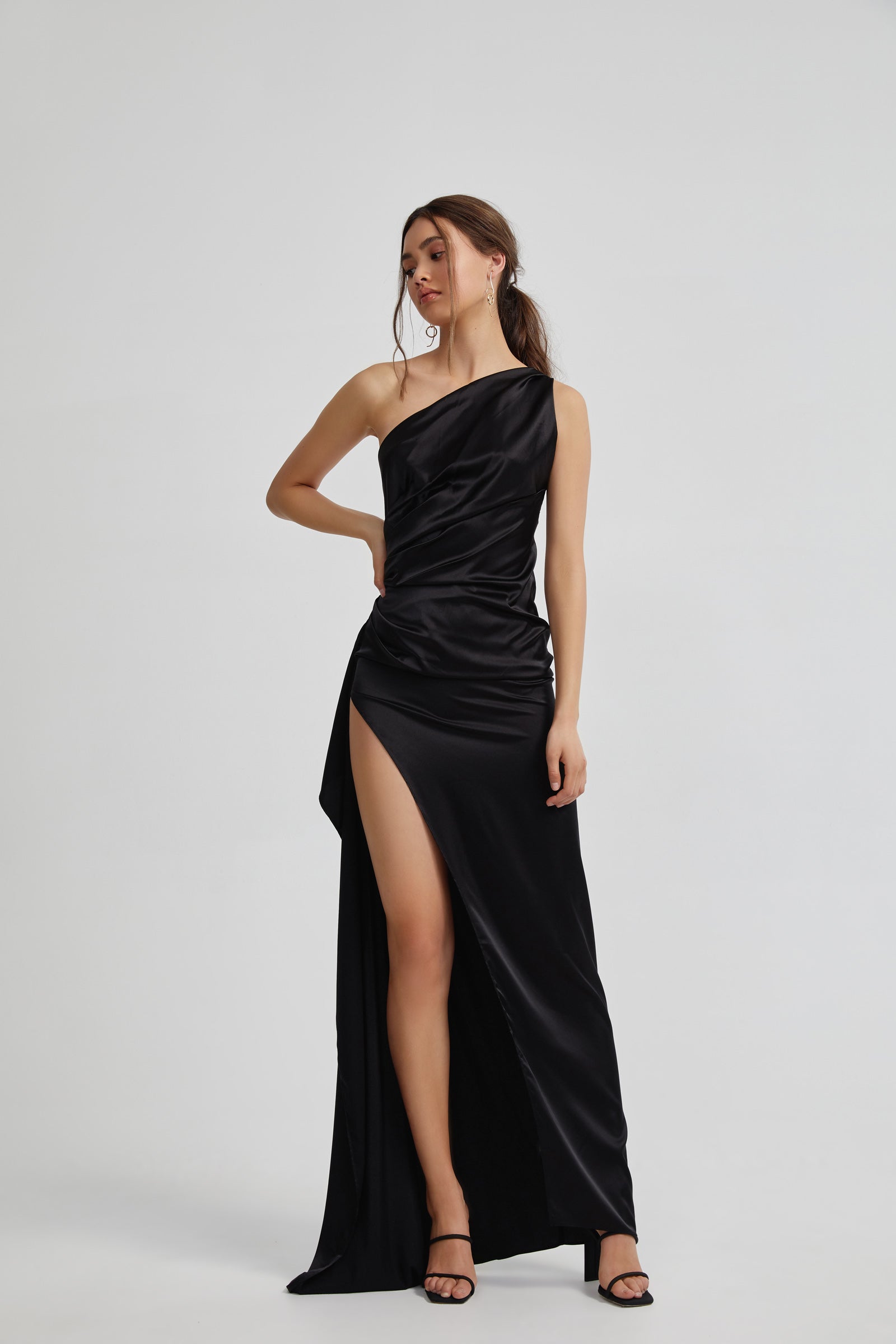 Samira Dress with asymmetrical neckline, ruched detailing, backless design, and high leg split in black satin for formal occasions