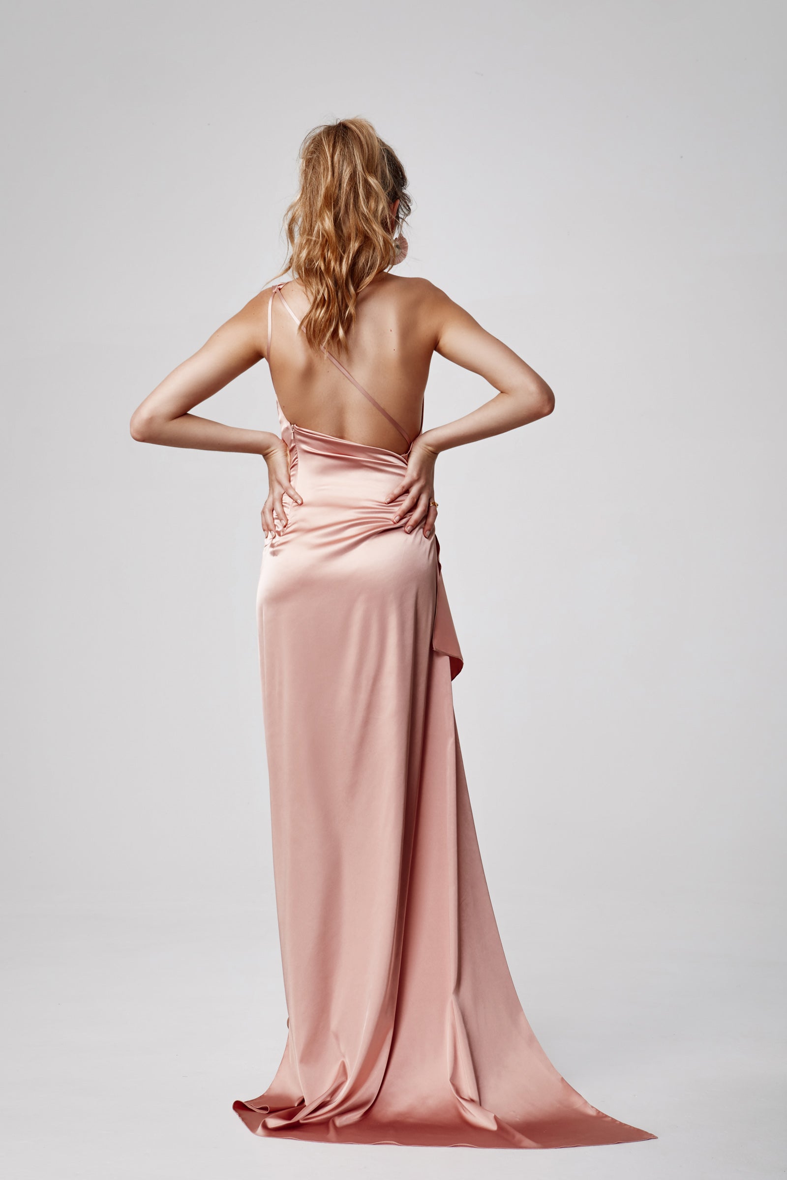 Samira Dress with backless design, delicate straps, and long flowing silhouette in soft pink satin for formal occasions