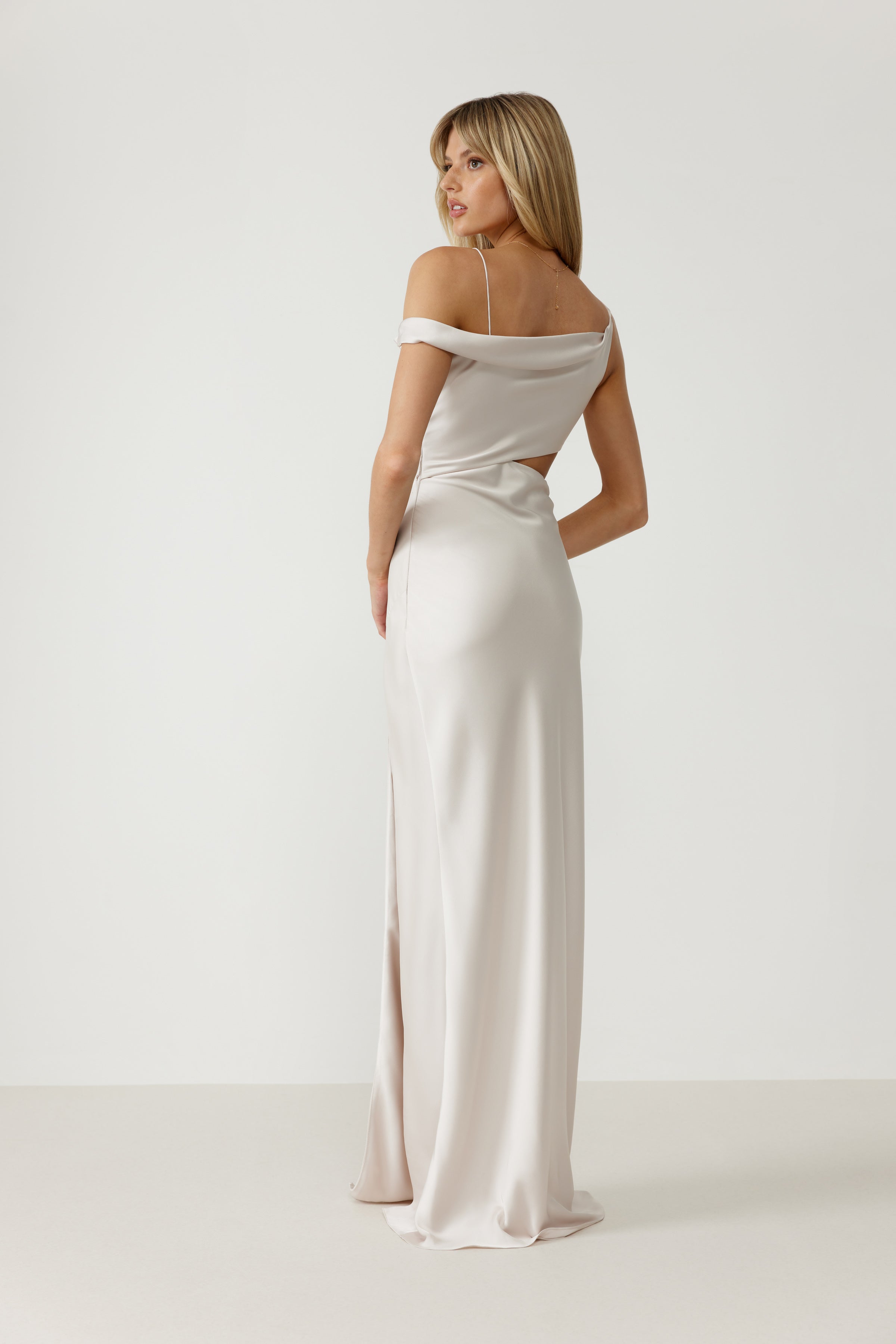 Zaria Dress featuring an off-shoulder sleeve, subtle back cutout, and split in pearl satin for formal black tie occasions